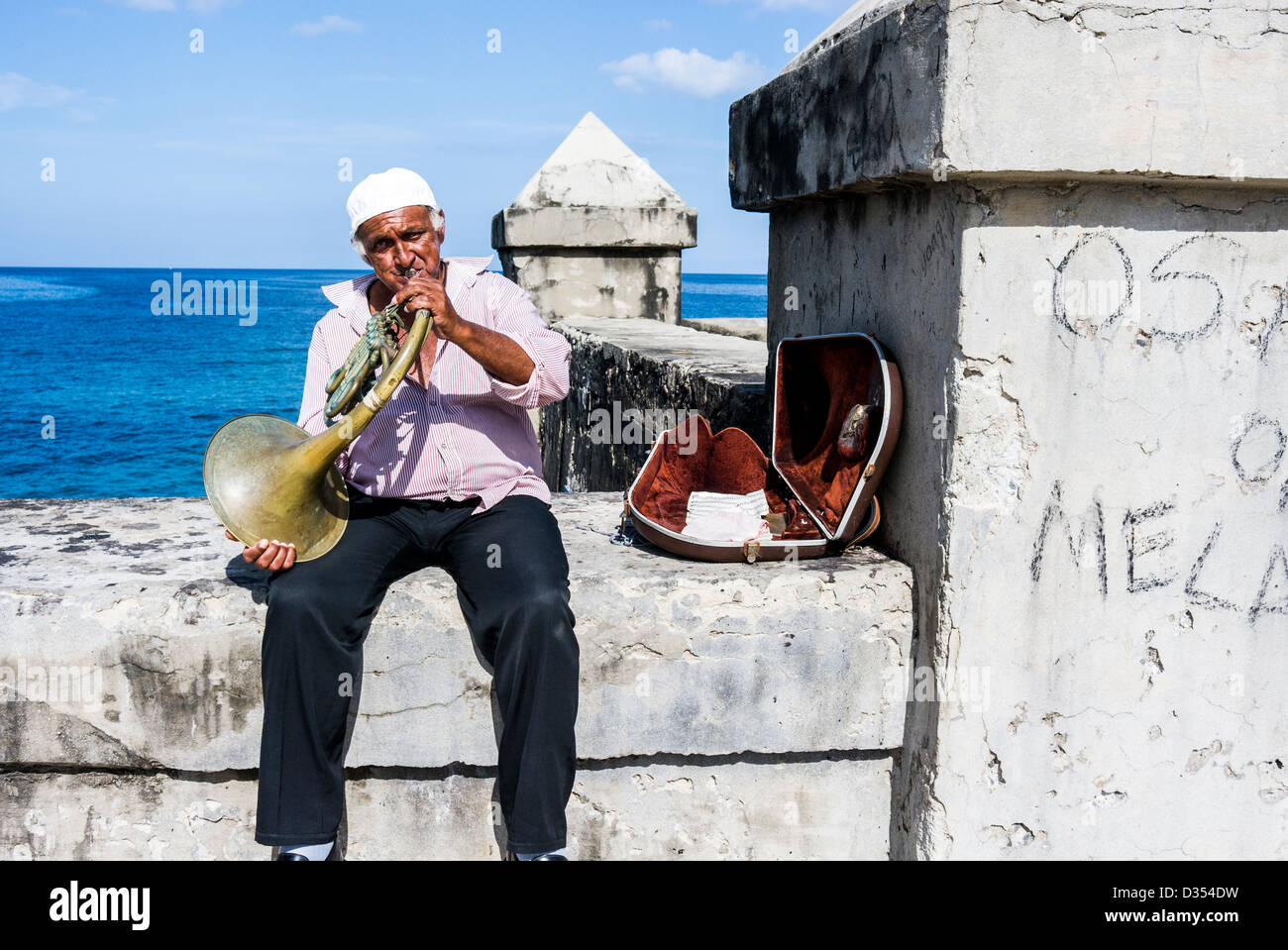 Man playing the french horn for pesos from tourists at the Malecon, Havana, Cuba Stock Photo