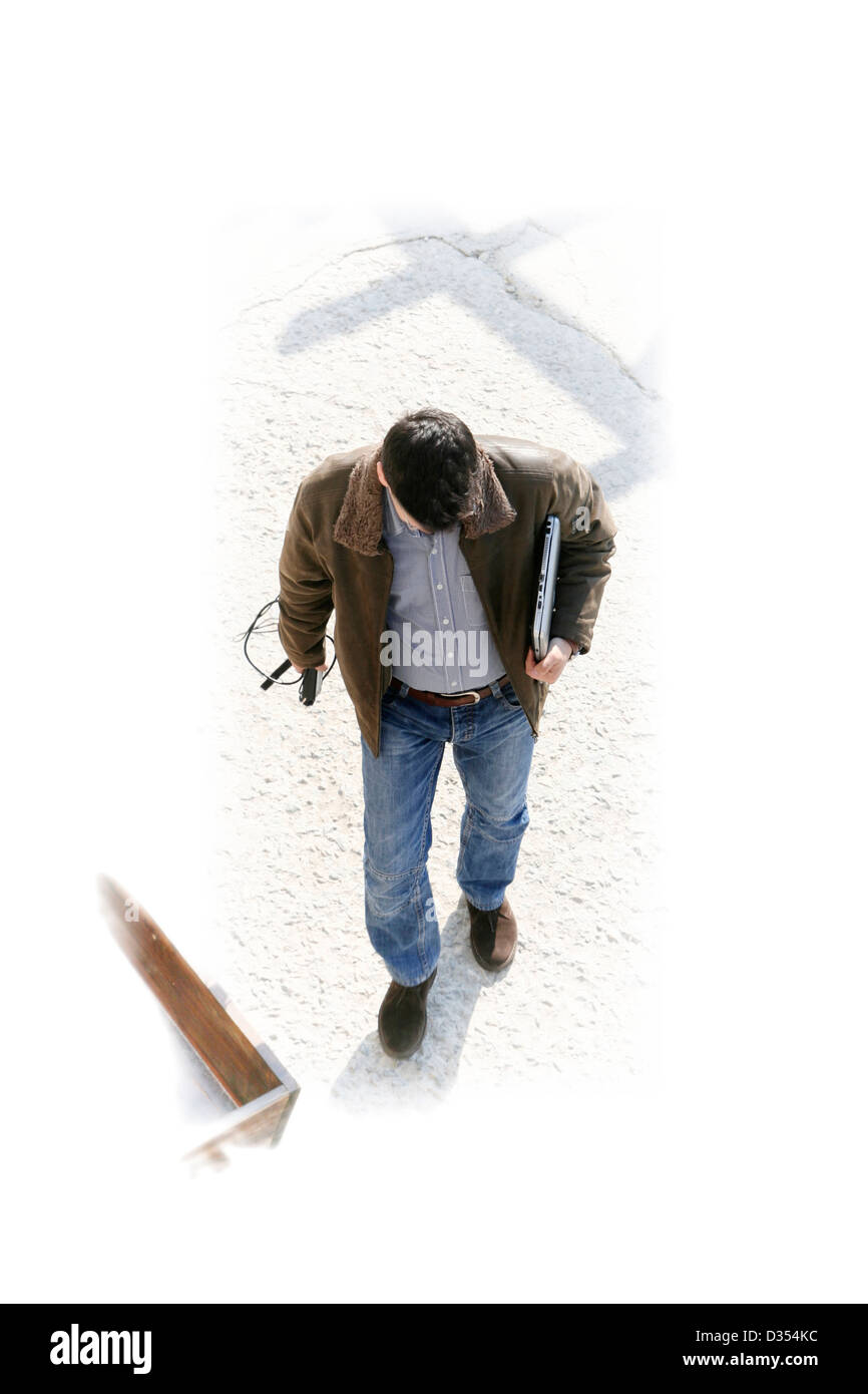 Man with laptop walking down the street. Stock Photo