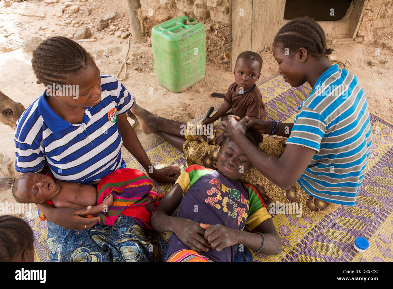 Barsalogho, Burkina Faso, May 2012: A woman braids her sister's hair in ...