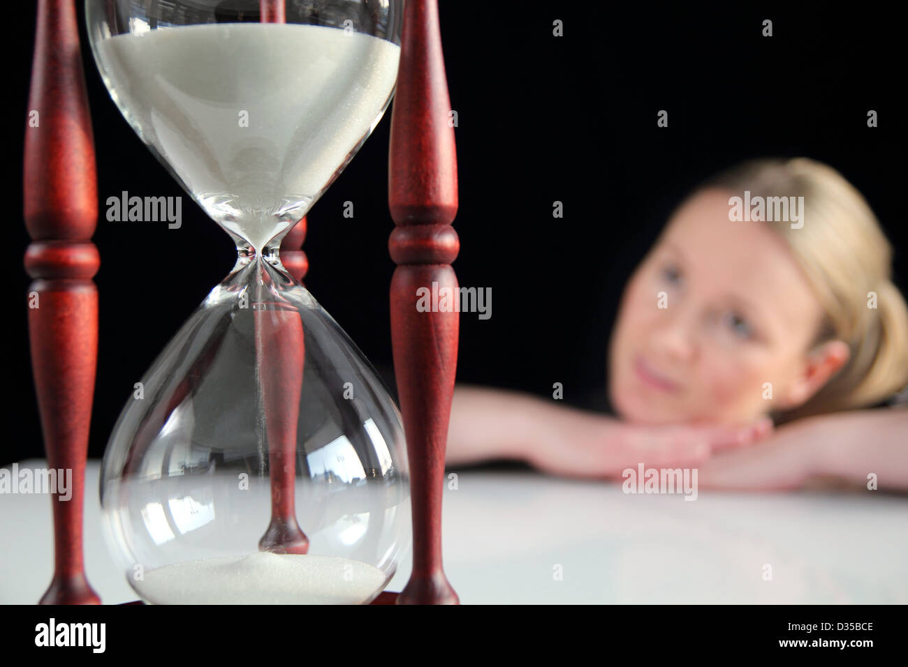 Young woman dreaming behind a big hourglass Stock Photo