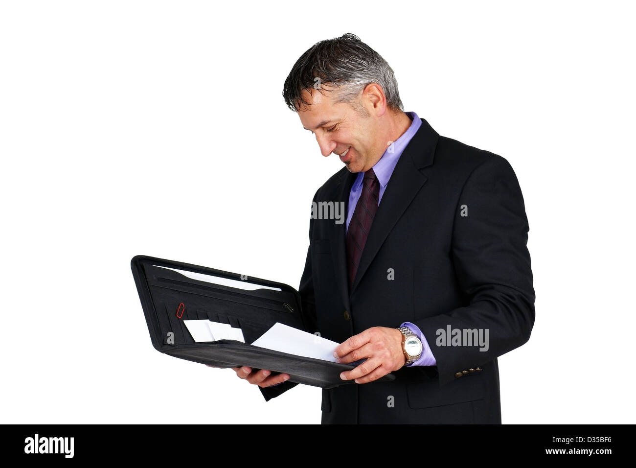Man in suit and tie, holding paperwork looking at it and smiling, can be boss or management employee. Stock Photo