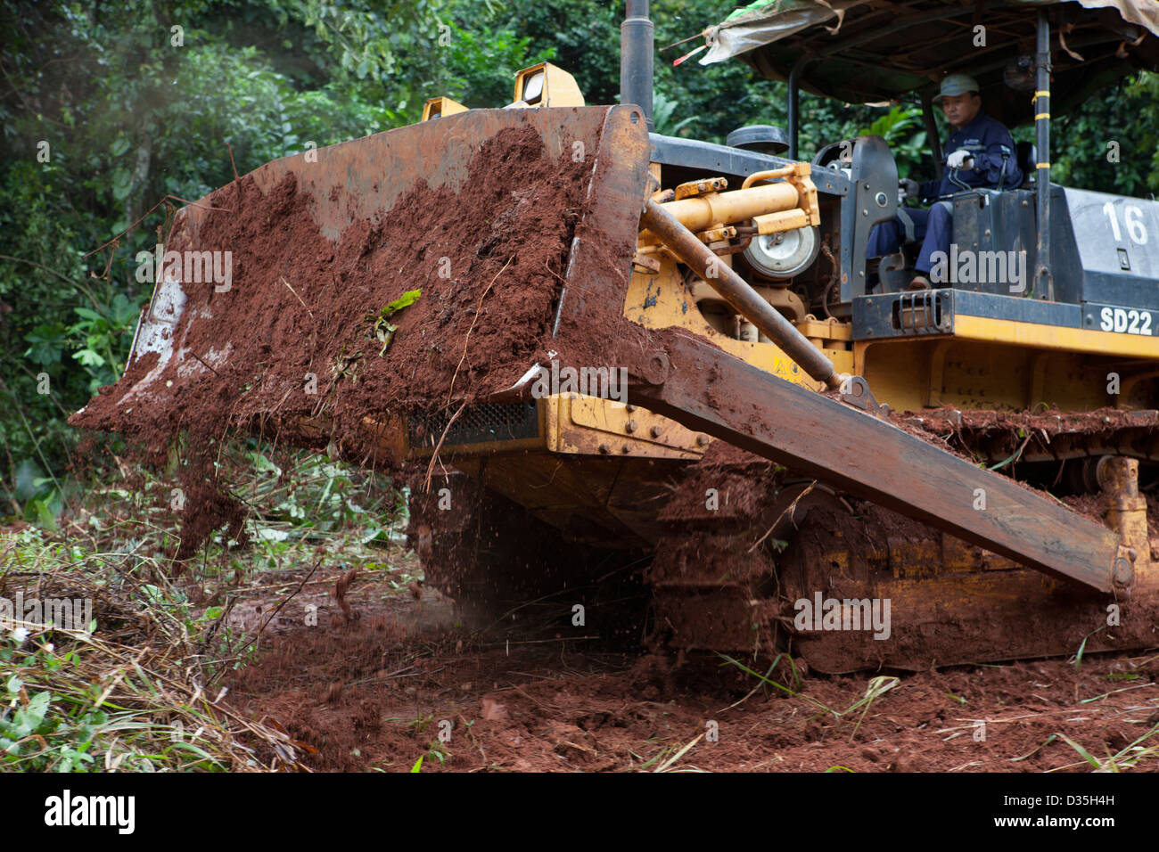 CONGO, 27th Sept 2012: A Chinese bulldozer driver from company Sinohydro cuts a path through the forest for a major new tarmac road. Stock Photo