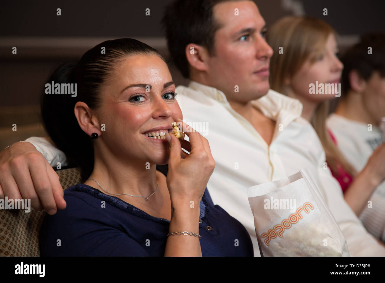 A woman enjoys an evening with friends in a cinema or theatre with popcorn Stock Photo