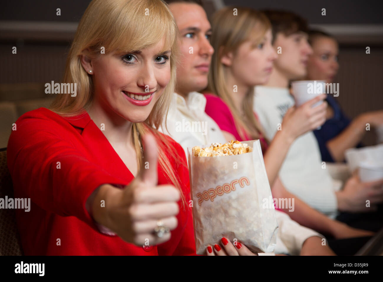 woman in cinema with a bag of popcorn showing thumbs up Stock Photo