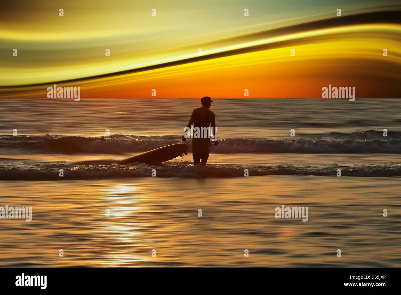 Scenic view with distorted landscape and sky with silhouetted figure with surf board Stock Photo