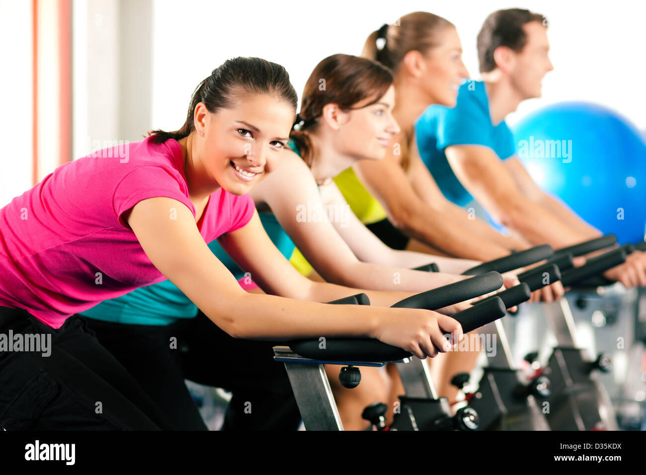 Group of four people spinning in the gym, exercising their legs doing