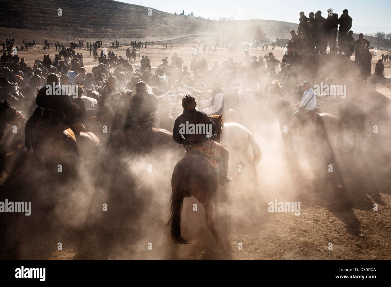 Sunlight and dust streams around buzkashi players in Sharinav ...