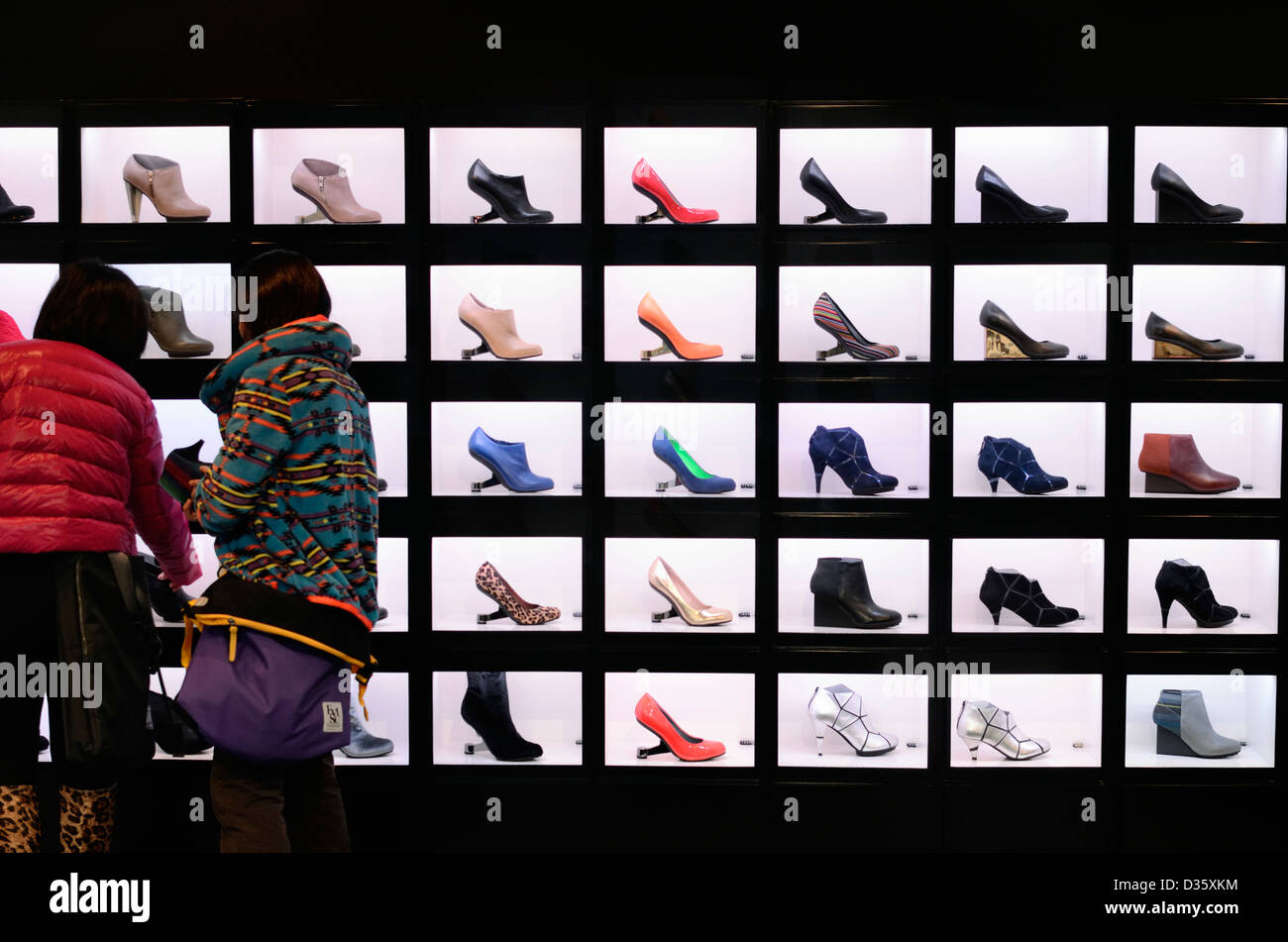 Female shoppers examining a shop display of brightly coloured shoes Stock Photo