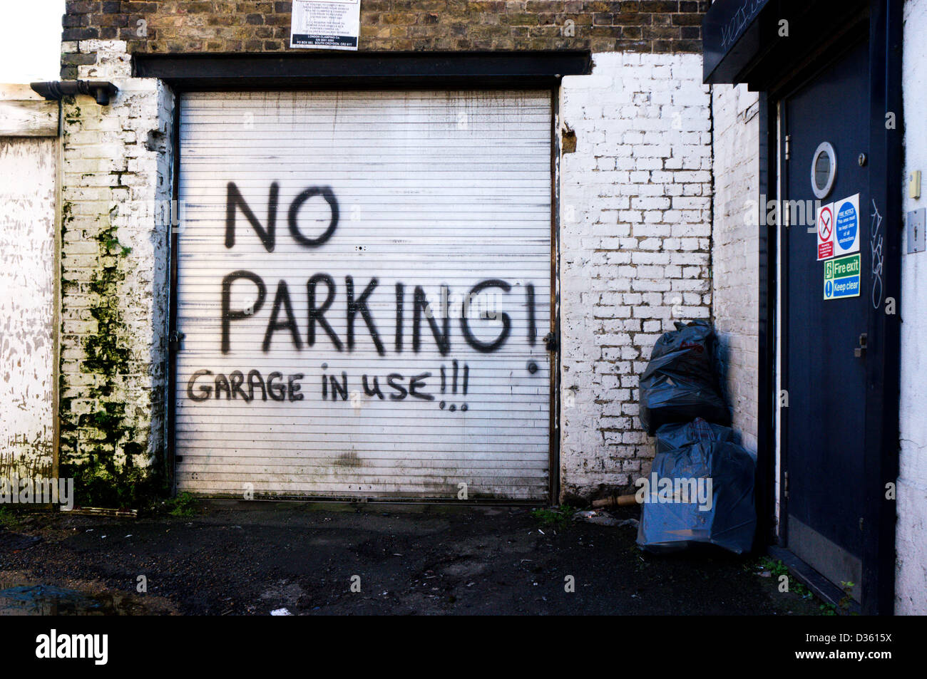 No Parking! Garage in Use!!! sign spray painted on roller shutter door. Stock Photo