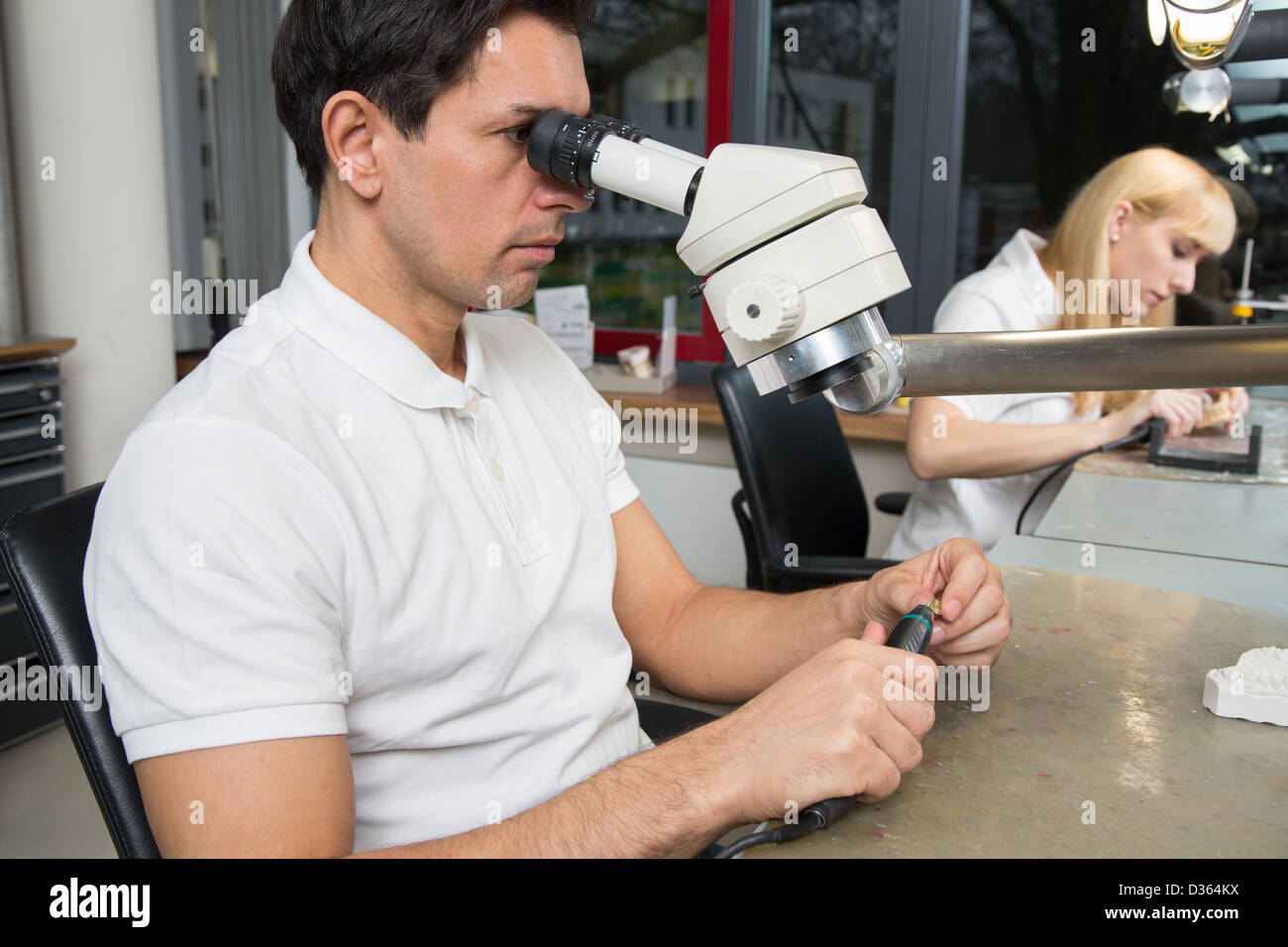 Two dental technicians at their workplace polishing dental prosthesis