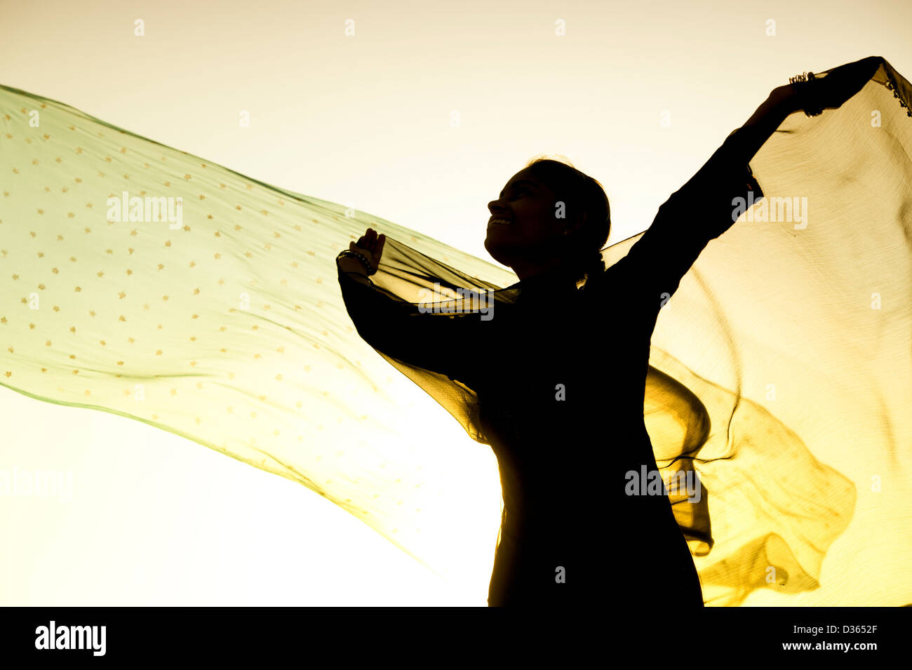 Indian girl with veils turning in the wind towards the sun. Silhouette. India Stock Photo