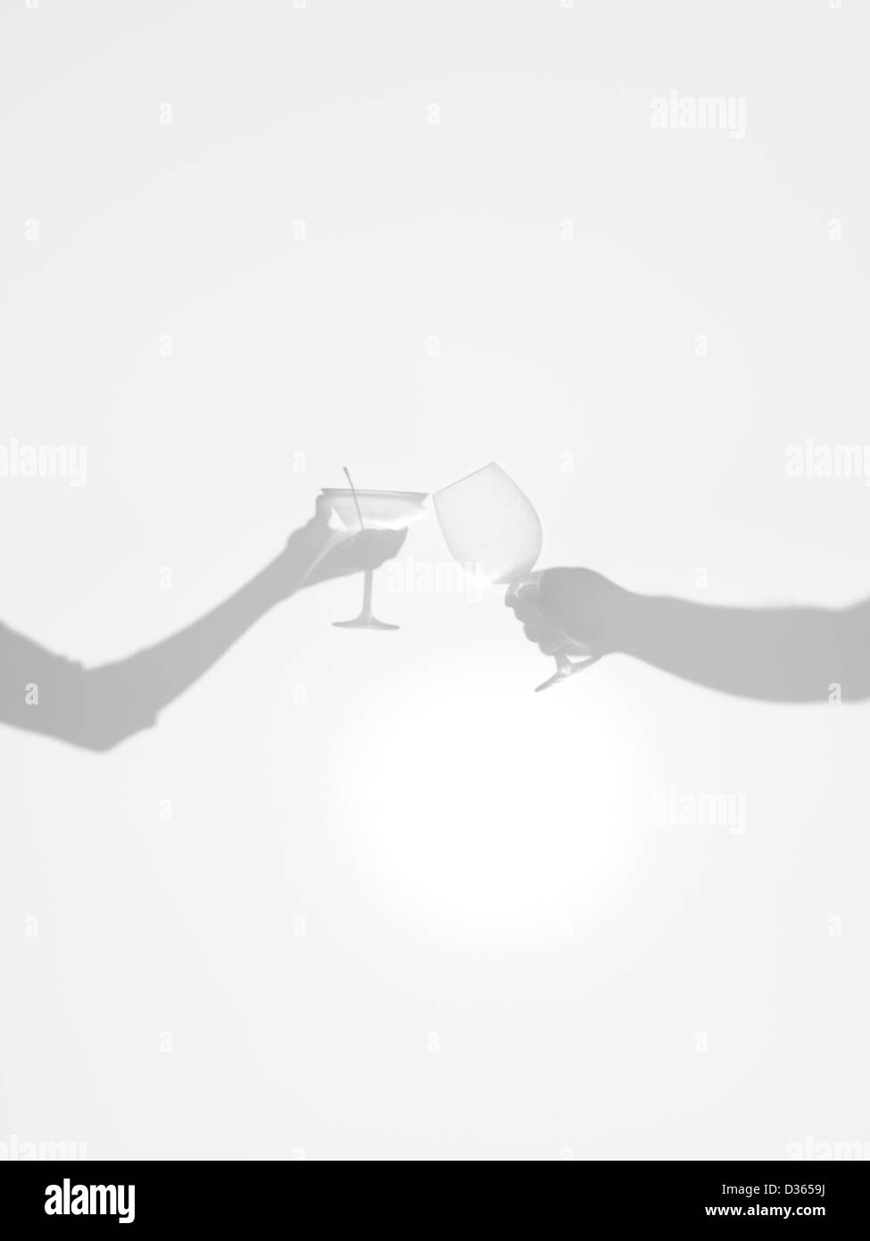 close-up of two hands silhouettes holding two different glasses, behind ...