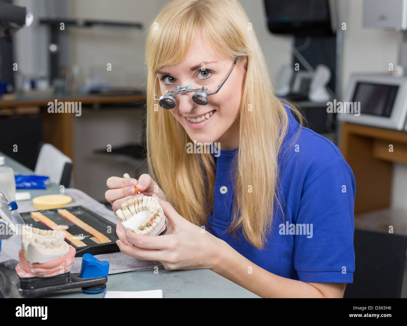 Dental lab technician with surgical loupes applying porcelain to