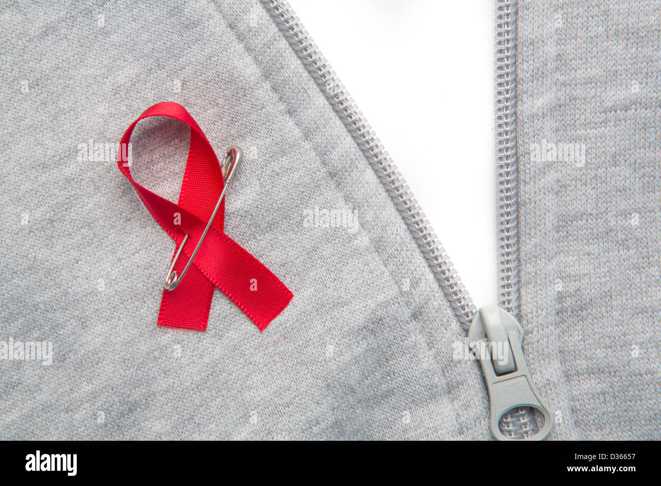 Aids awareness ribbon pinned on to grey zip jumper Stock Photo