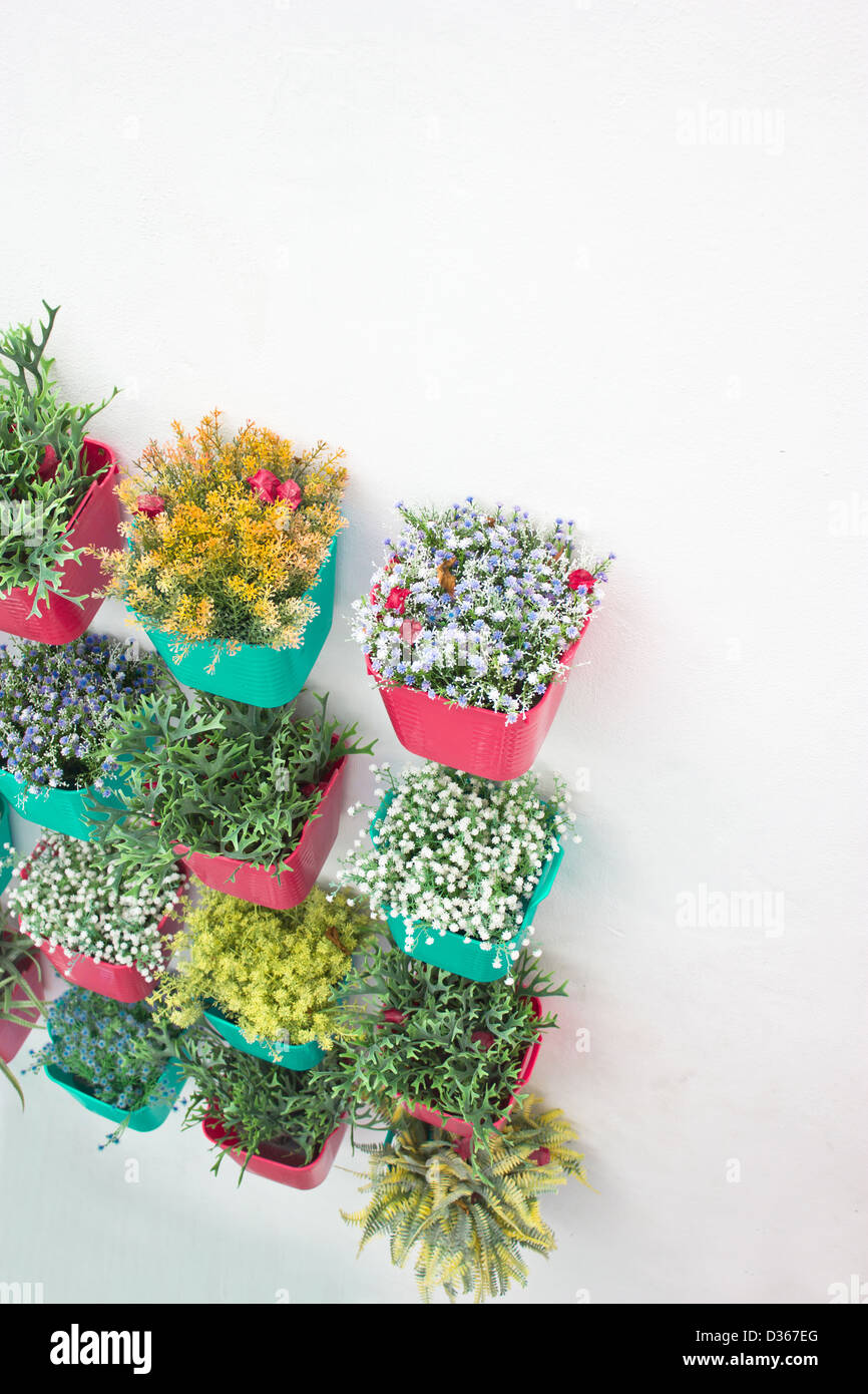 Plastic flowers with colorful plastic vase hang in row on the wall
