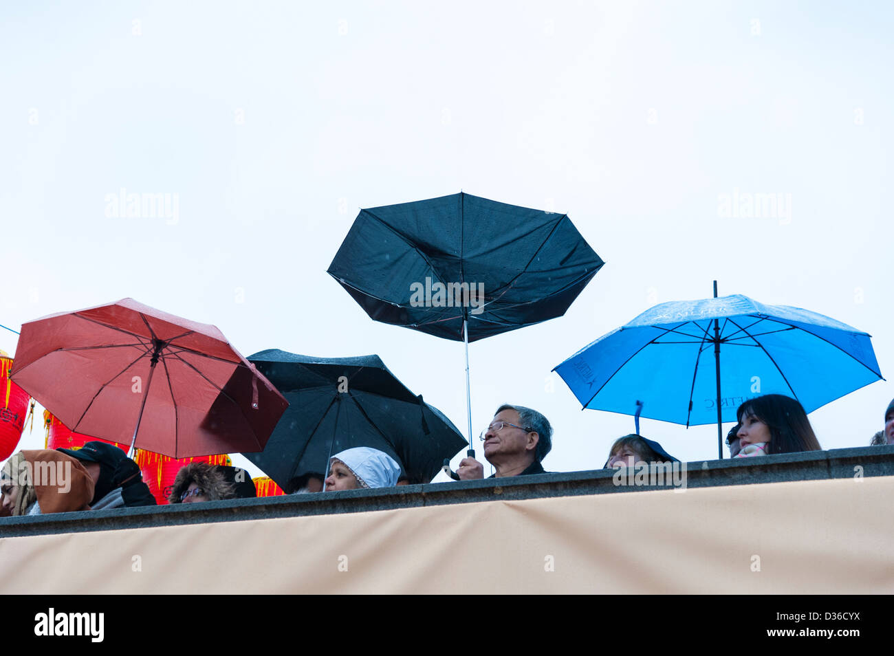 People under umbrellas in the rain watching festivities at the Chinese New Year Celebrations London 2013 Stock Photo