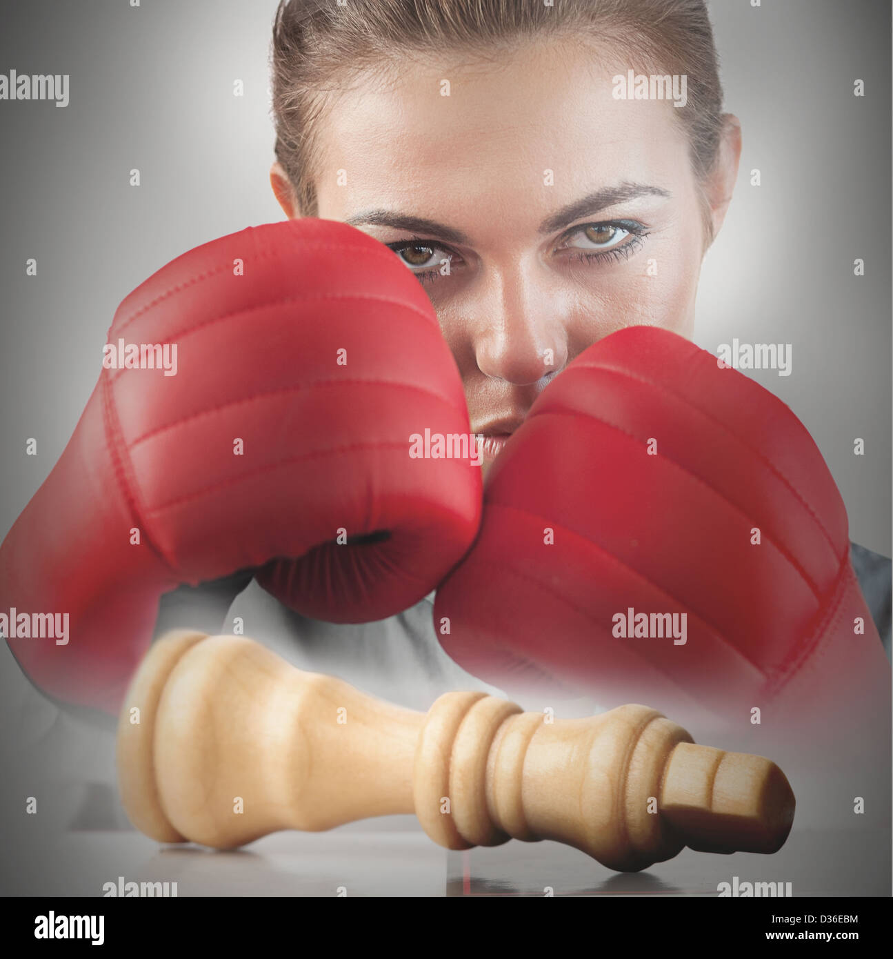 Powerful female boxer with knocked chess piece Stock Photo