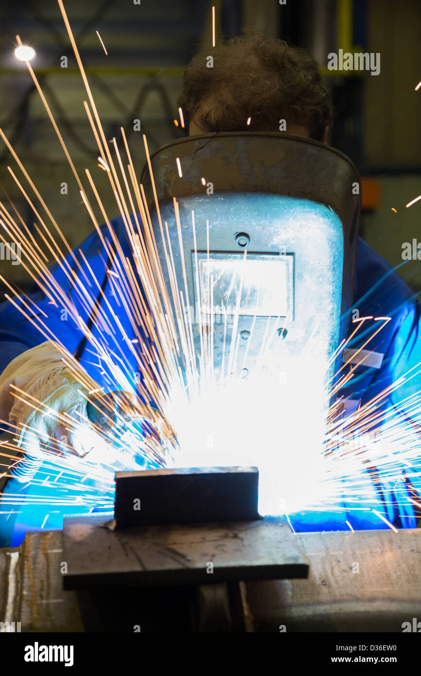A construction worker and welder is welding steel parts with a lot of sparks Stock Photo