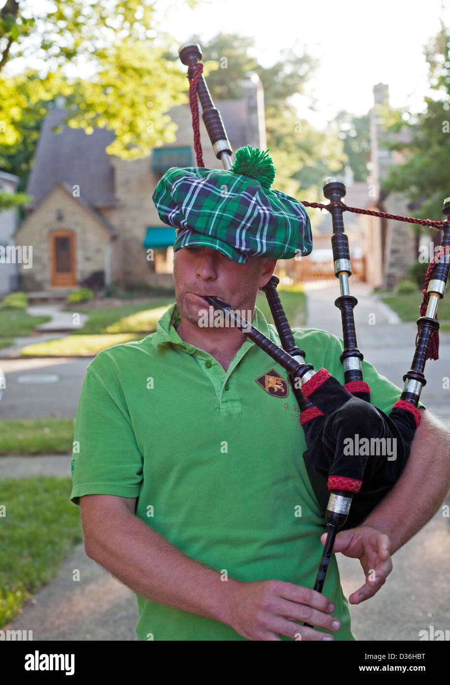 A man wearing a traditional plaid hat plays the bagpipes. Stock Photo