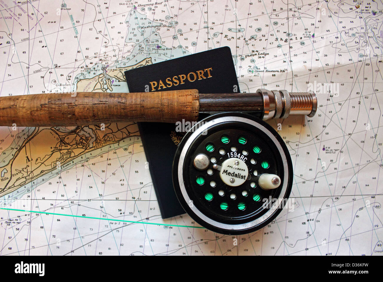 A flyrod and reel rests on a nautical chart with a passport. Stock Photo