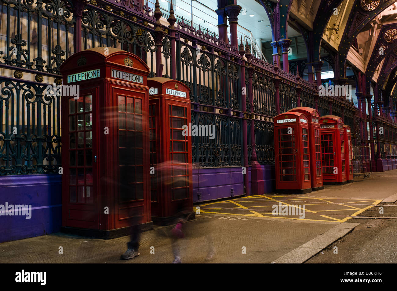 Ghostly figures walking past red telephone boxes at Smithfield Meat Market Stock Photo