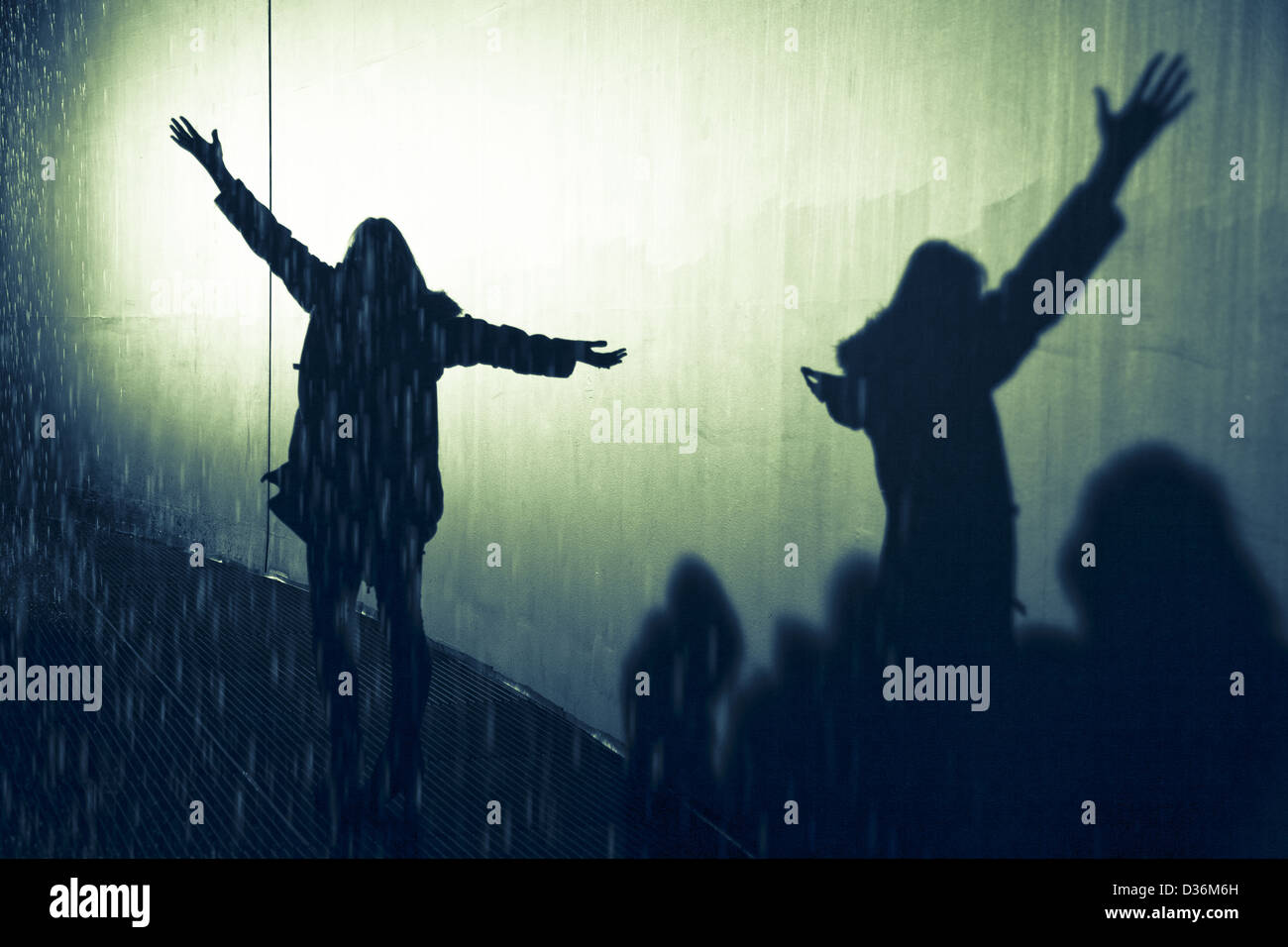 shadow of silhouette woman in the rain with arms open and outstretched enjoying the rain Stock Photo