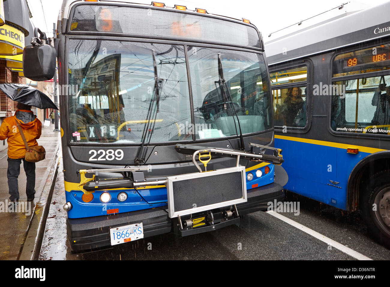 Vancouver busses at bustop passing on a wet rainy day BC Canada Stock Photo