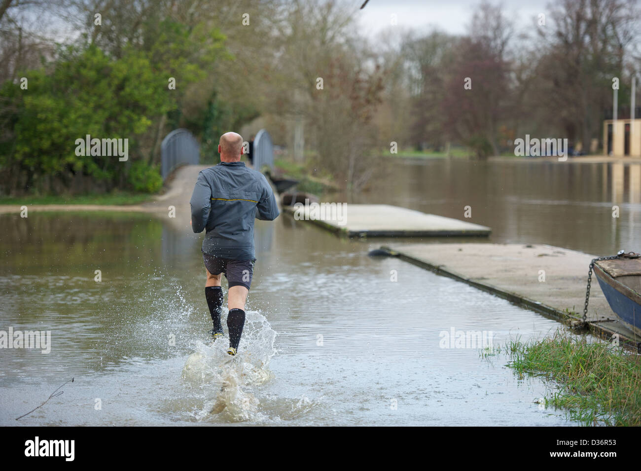 Man running through flooded path next to the River Thames in Oxford. Stock Photo