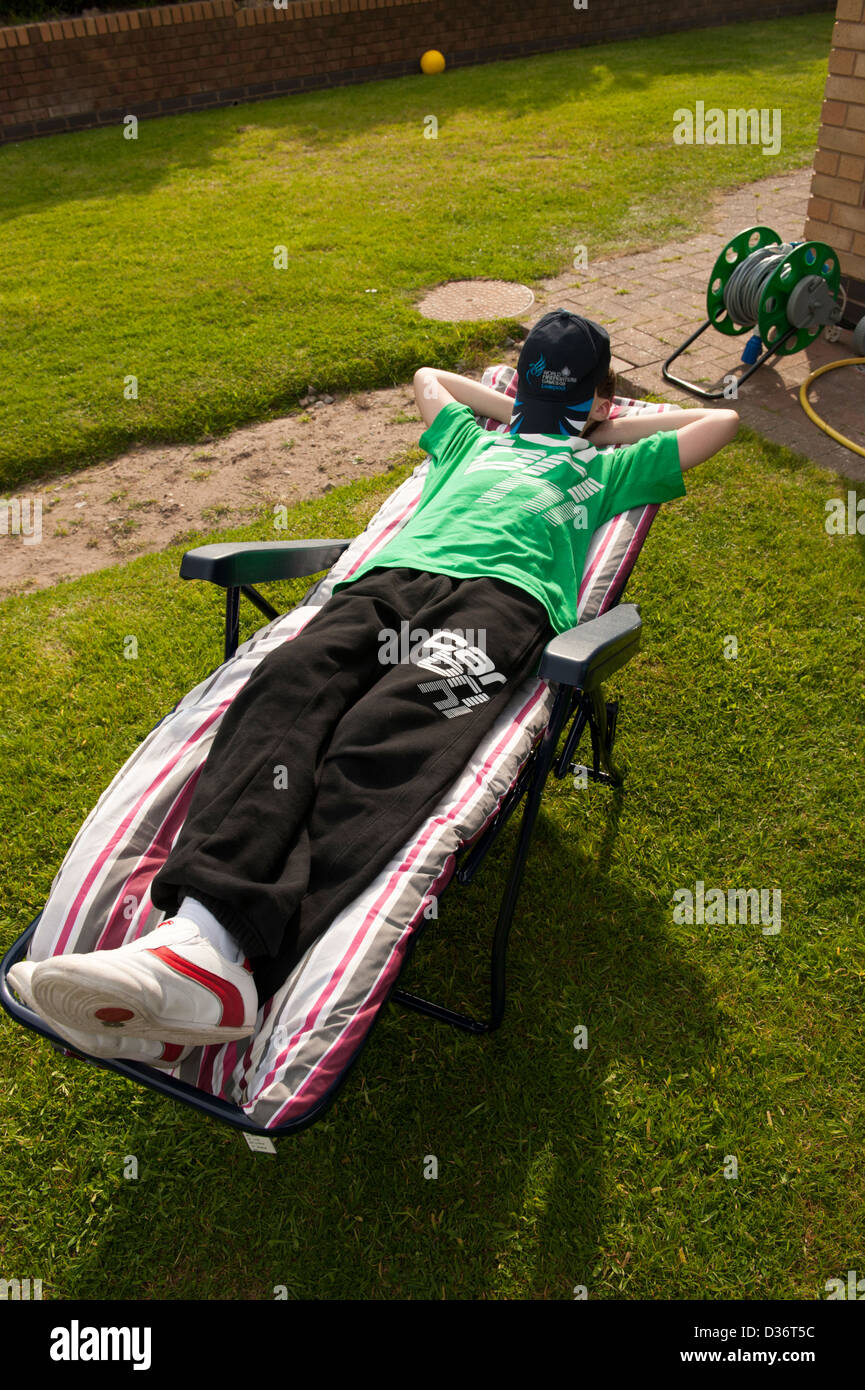 Teenage boy relaxing in sun on lounger FULLY MODEL RELEASED Stock Photo
