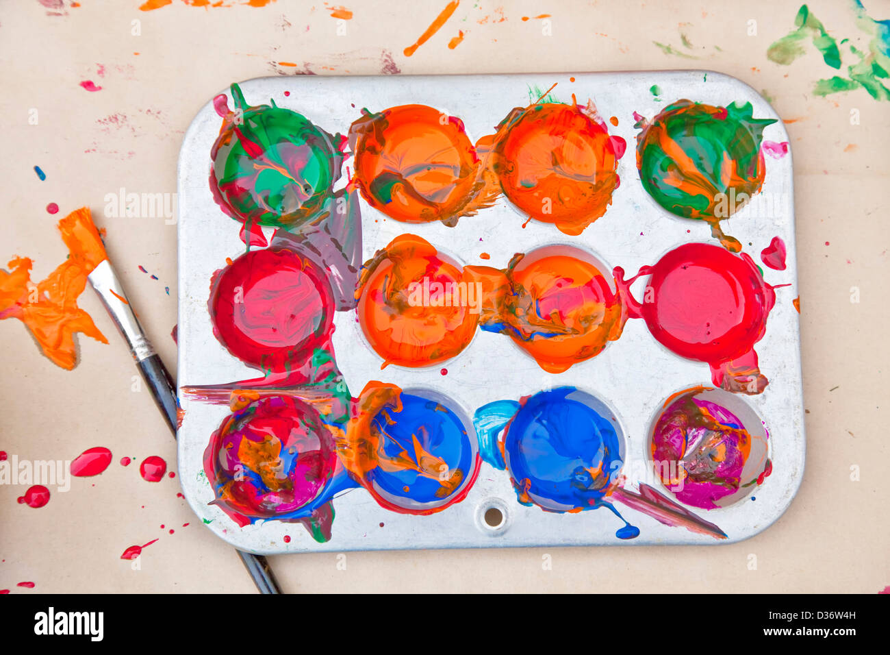 Messy array of colors of children's paint in a tray with a paint brush Stock Photo Alamy