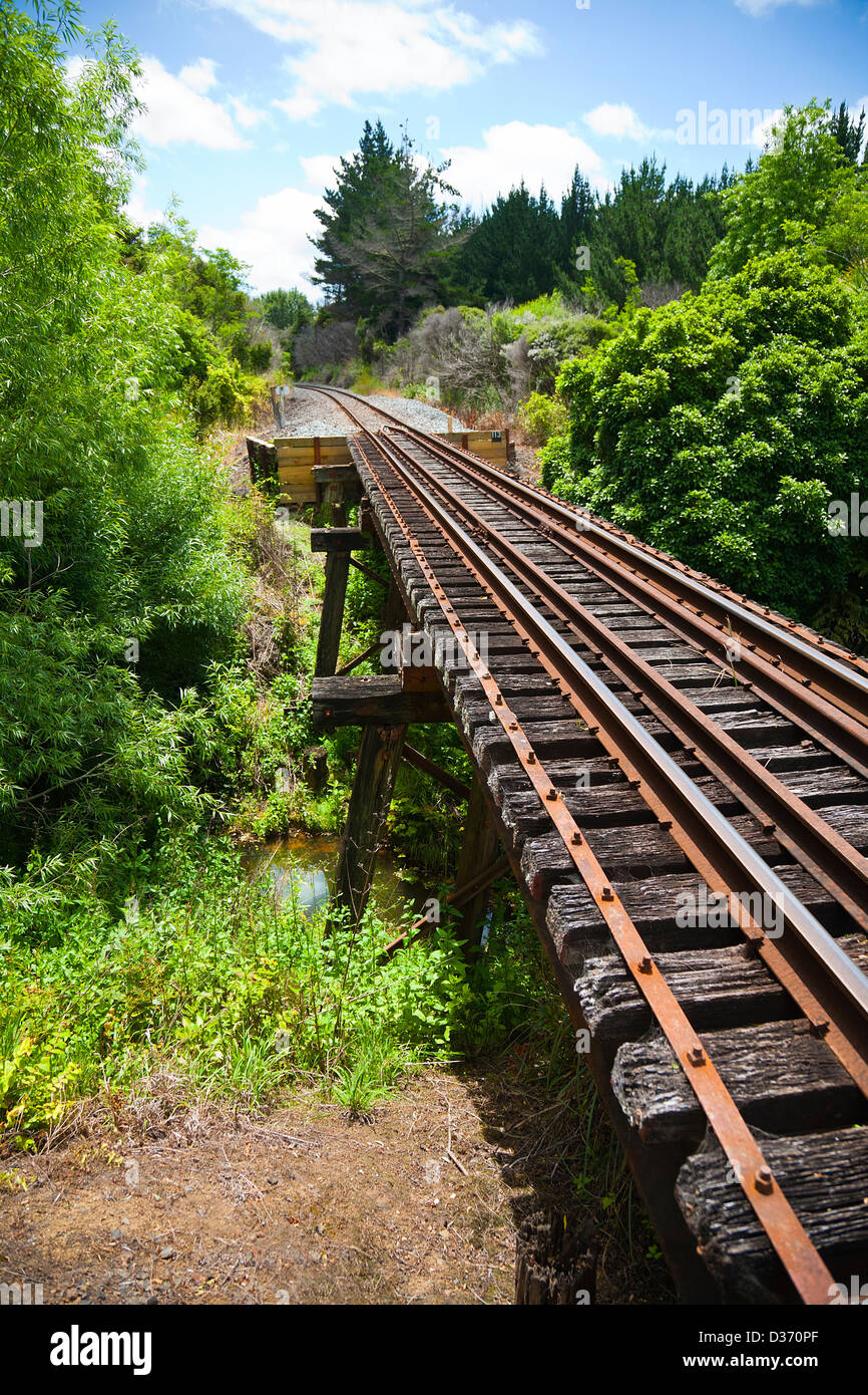 A view along a working railway track on an old trestle bridge over a river. Northland, North Island, New Zealand. Stock Photo