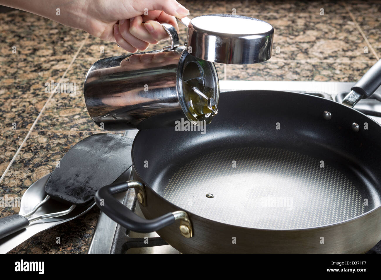 Photo of female hand adding cooking oil to frying pan in preparation of