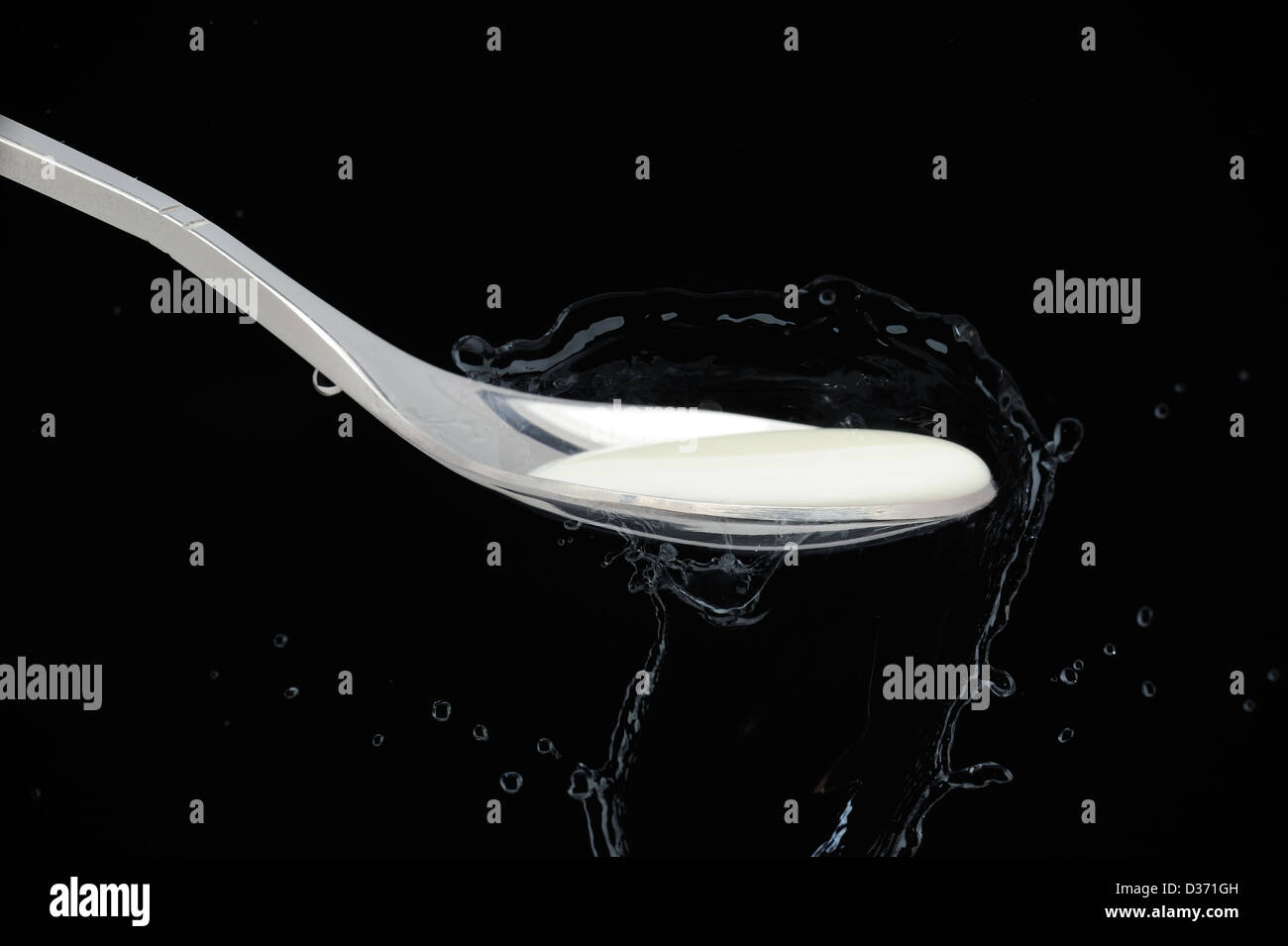 Silver Teaspoon with full cream milk in isolated black background Stock