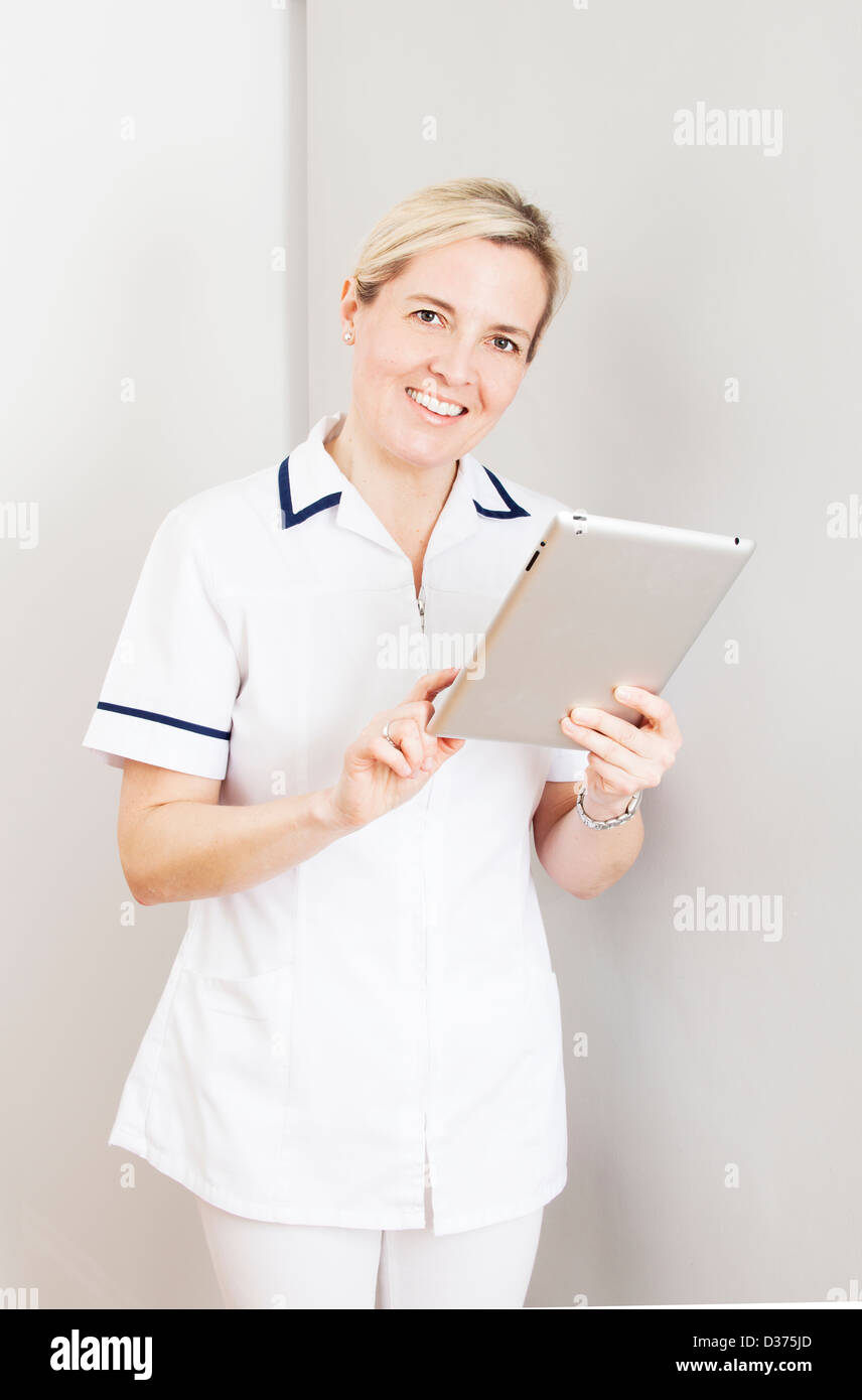 Smiling female wearing a white medical uniform holding a digital tablet ...