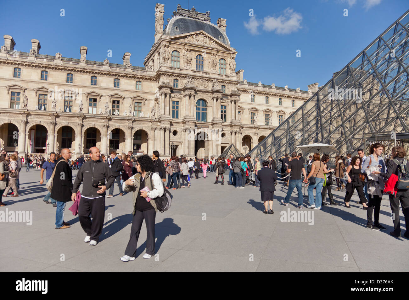 People in courtyard of the Louvre in Paris, France: the world's most visited museum. Pei's glass pyramid is the main entrance. Stock Photo