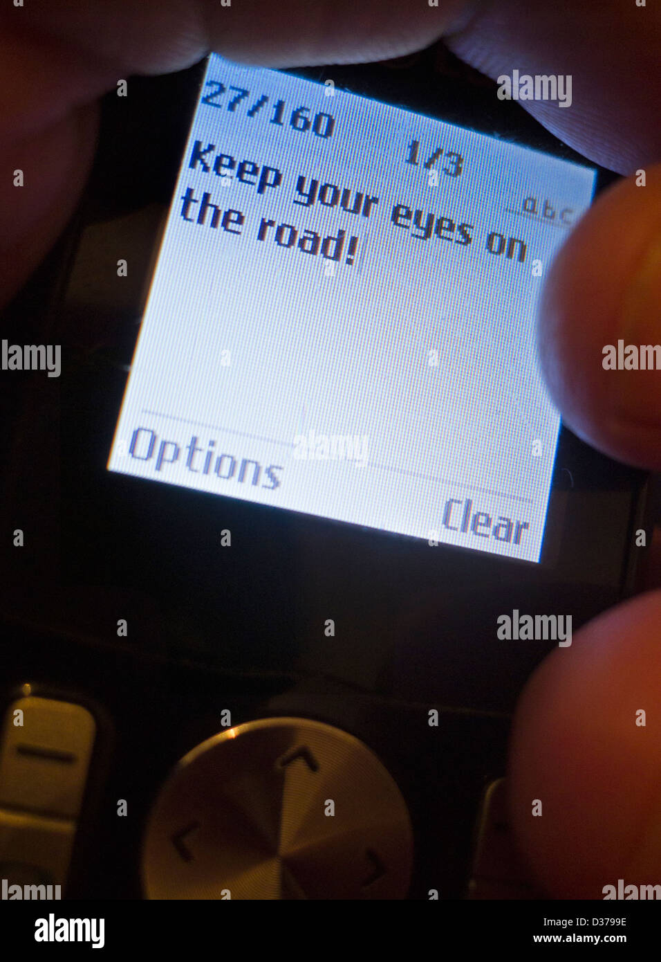 Text message 'Keep your eyes on the road!' on a mobile phone in the hand of a male driver. Stock Photo