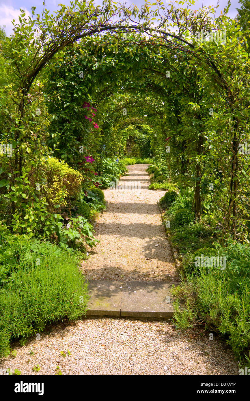 UK gardens. A rose arch walk with clematis and honeysuckle. Stock Photo