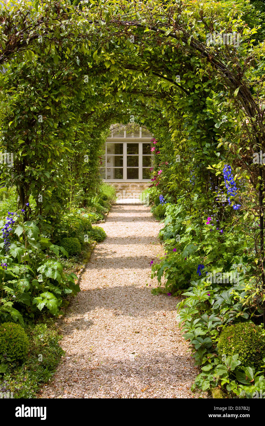 UK gardens. A rose arch walk with clematis and honeysuckle. Stock Photo