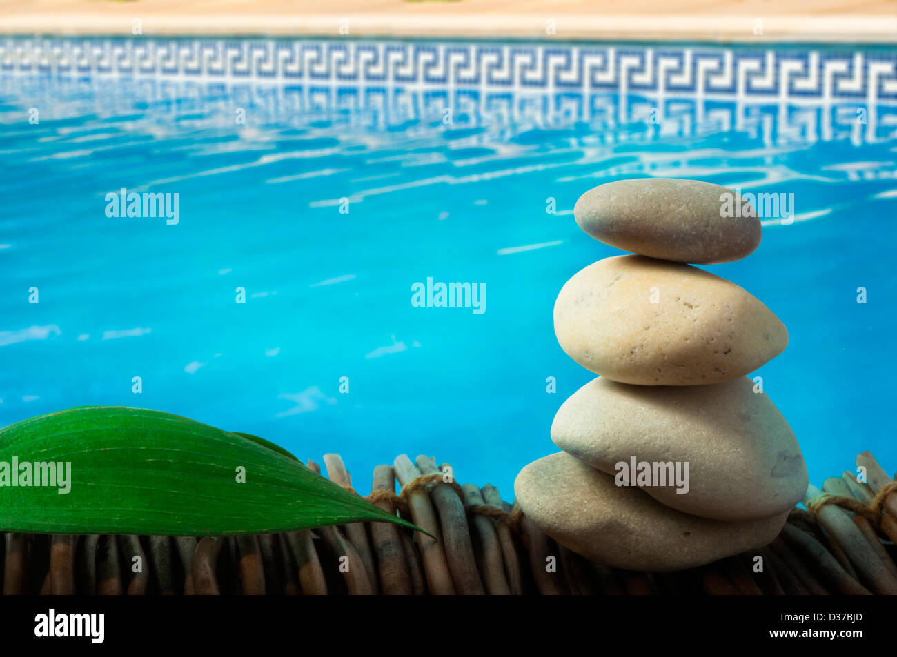 Stacked stones on wooden base for spa and green leaf. Swimming Pool on