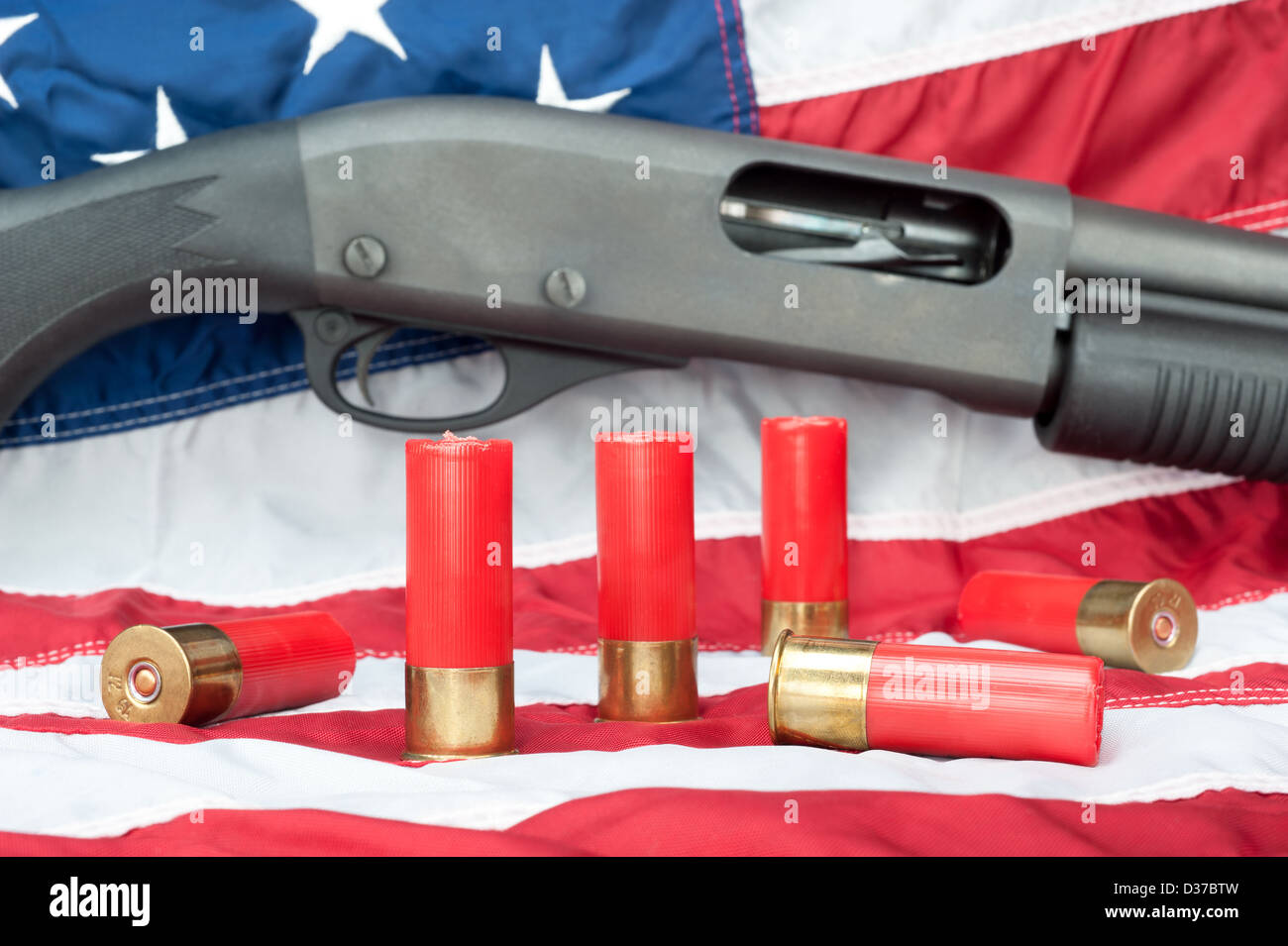 A pump action shotgun with several shells of ammo resting on an American flag Stock Photo