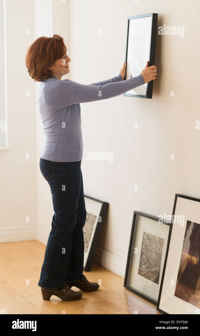 USA, New Jersey, Jersey City, Woman hanging picture on wall Stock Photo