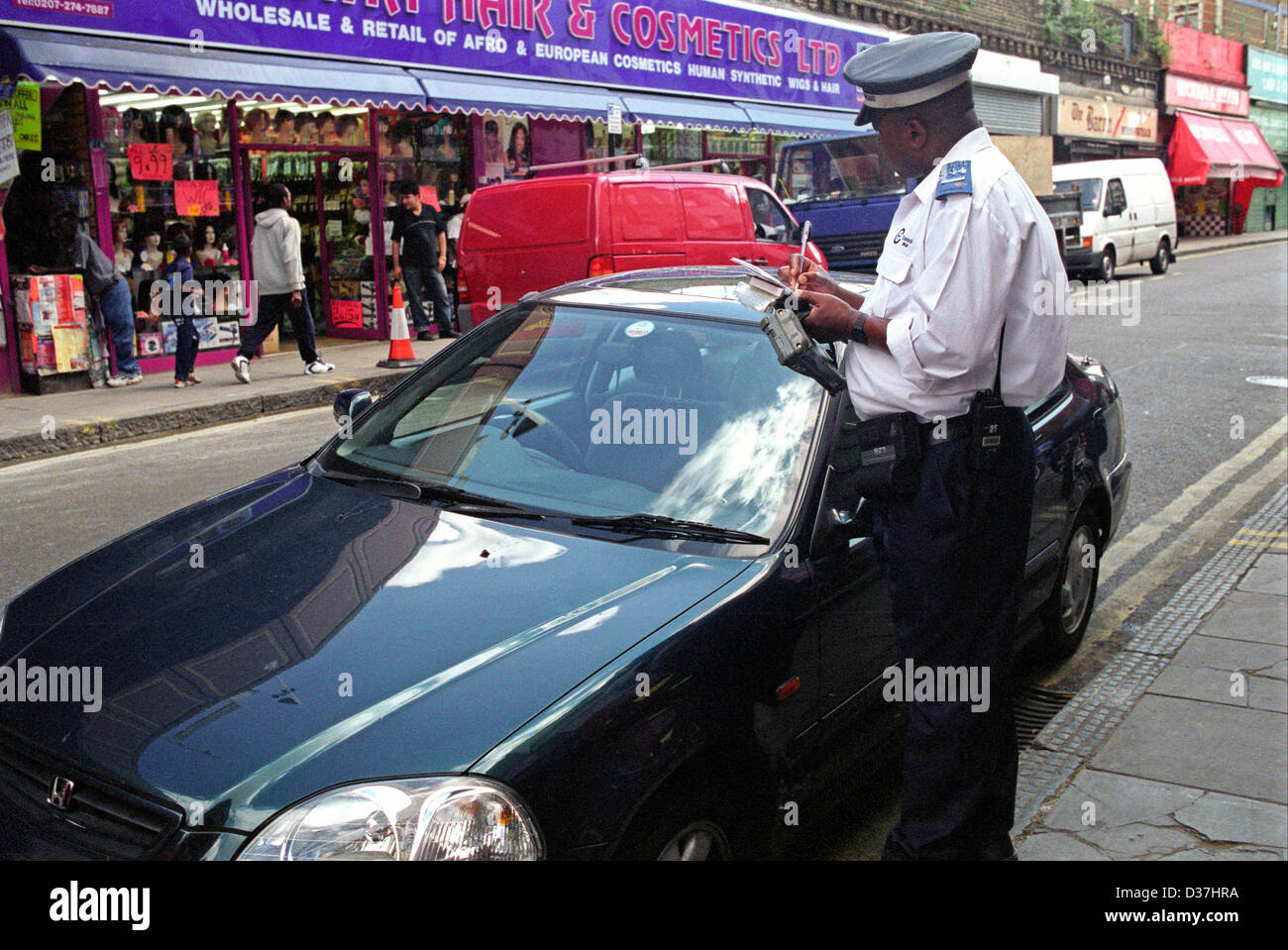 Traffic warden ticketing car in central London Stock Photo