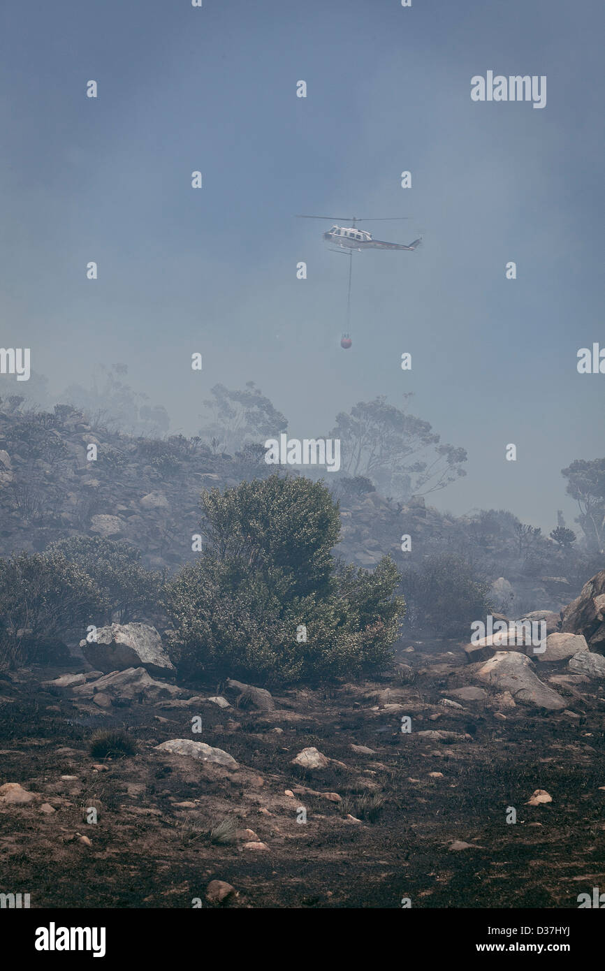 A yellow Helicopter is used to bring raging fires in Hout Bay under control. Stock Photo