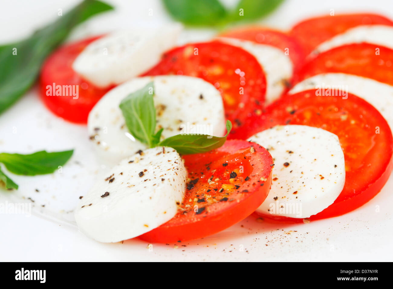 Tomato and mozzarella with basil leaves on a plate Stock Photo - Alamy