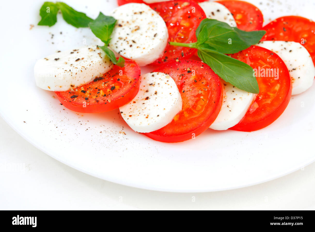 Tomato and mozzarella with basil leaves on a plate Stock Photo - Alamy