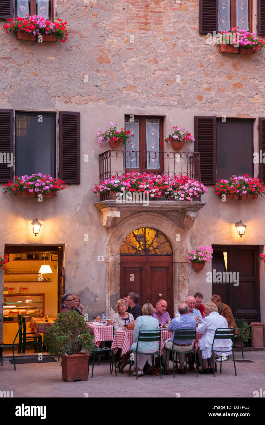 Group of tourists enjoying an evening meal at an outdoor cafe in Pienza, Tuscany Italy Stock Photo