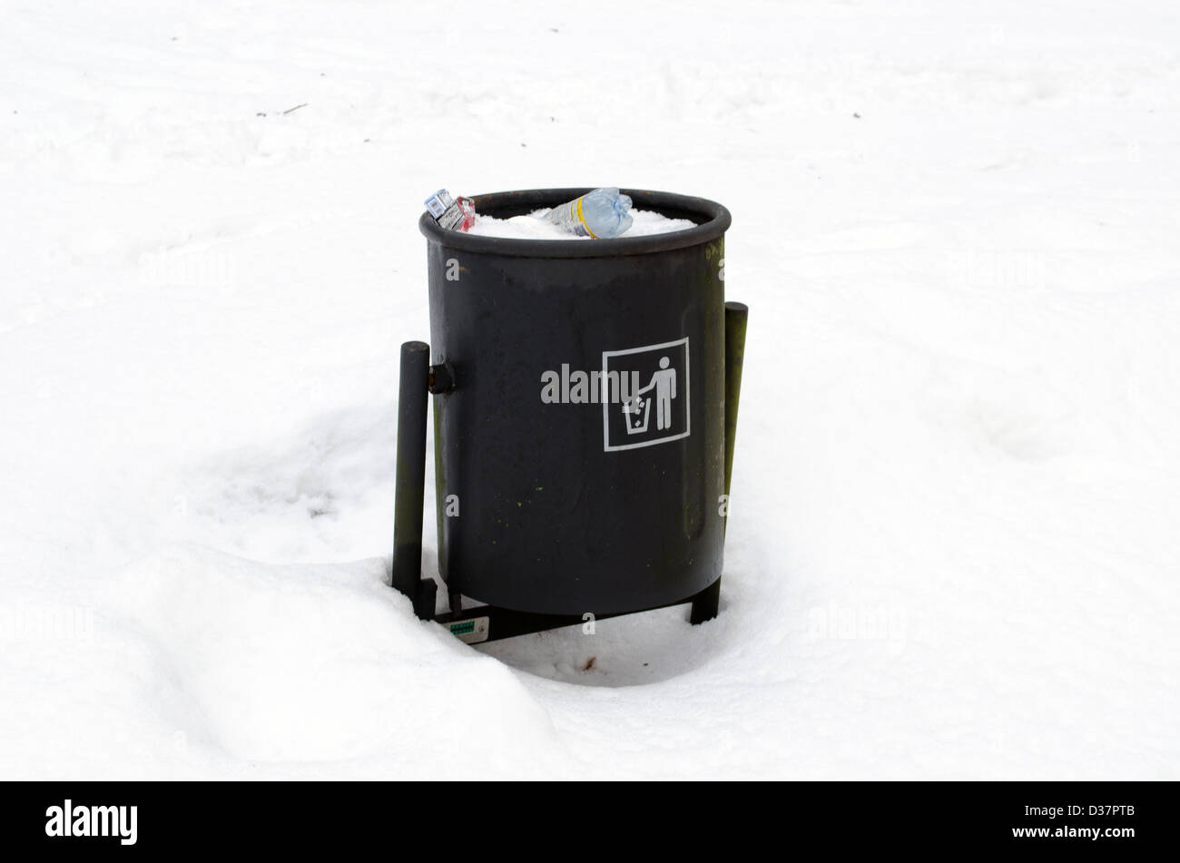 full garbage dustbin waste bin surrounded by snow in winter park. Stock Photo