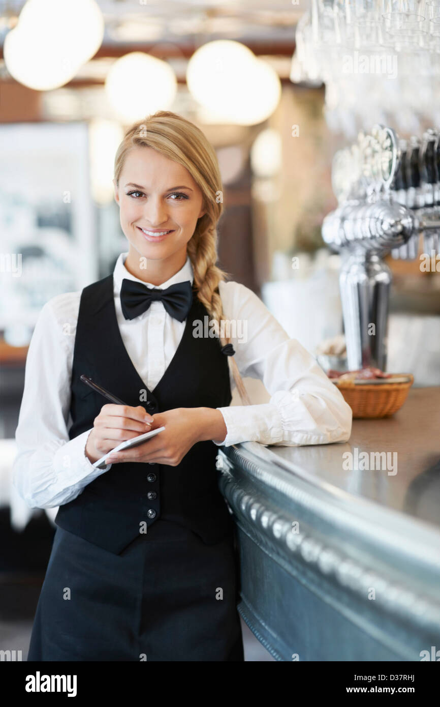 Denmark, Aarhus, Portrait of smiling waitress standing by bar counter Stock Photo