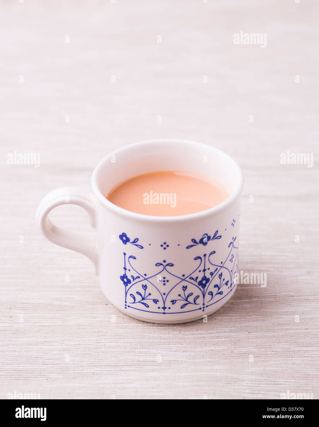 Cup of Rooibos (red bush) tea with milk in a vintage china teaset with a old spoon against a