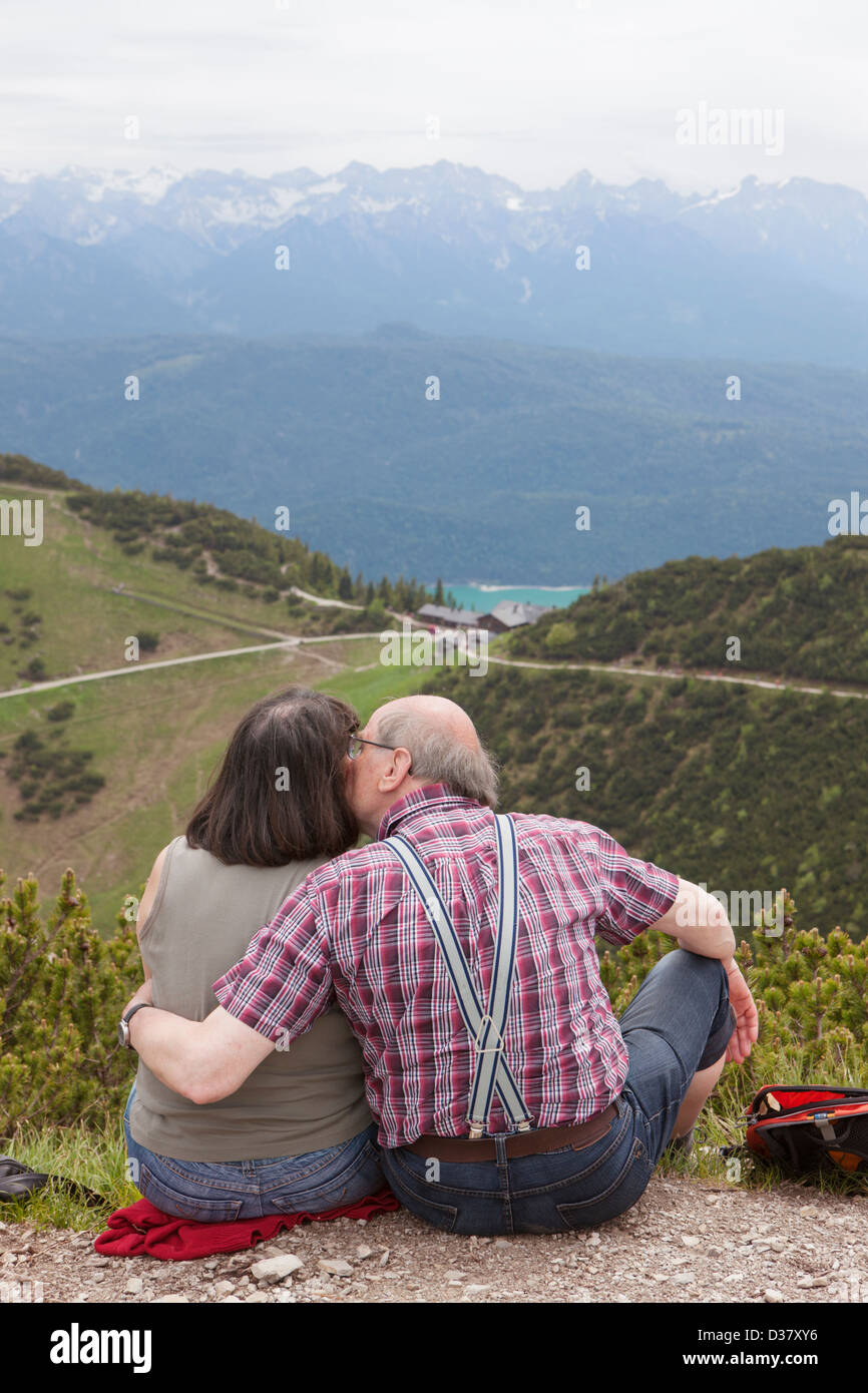 Old couple looking at the view from Herzogstand and kissing, Bavaria, Germany Stock Photo